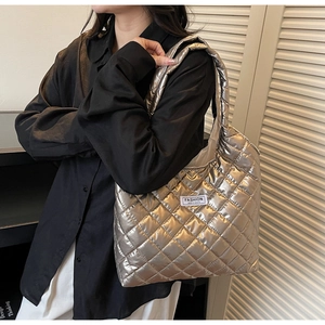 Detail of metallic quilted tote bag with white FASHION INSTINCT label on glossy texture