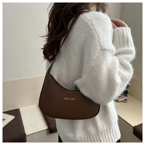 Brown leather crescent shoulder bag with gold logo shown on a model's shoulder