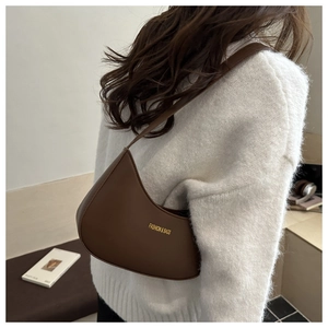 Detail of a deep brown faux leather hobo bag worn with a white knit sweater