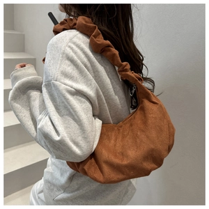 Détail du sac à main marron foncé en daim avec bandoulière à plis et design plissé