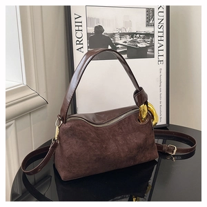 Gros plan d'un sac oreiller en daim marron foncé avec une boucle en métal doré épais