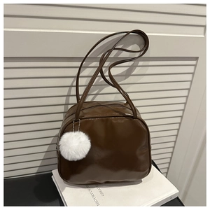 Detail view of dark brown glossy PU leather square bag with white plush pompom charm
