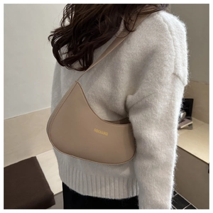 Detail of a beige leather crescent shoulder bag with Fashion & Bags text on a model