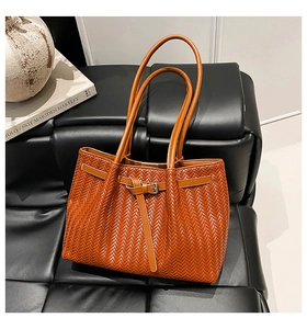 Detail of brown woven leather tote bag with V-shaped texture and metal buckle strap