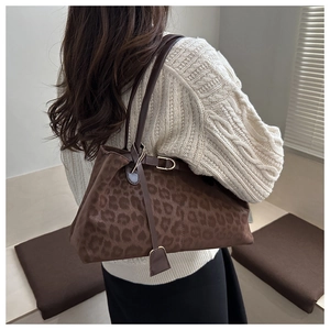 Detail of a large leopard print tote bag with brown straps and suede-like texture