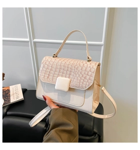 Détail de la texture crocodile beige et de la boucle carrée sur un sac à bandoulière chic