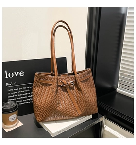 Close-up of brown woven leather tote bag with herringbone texture and metallic buckle