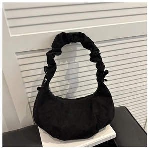Détail du sac hobo en daim noir avec bandoulière froncée sur fond blanc minimaliste