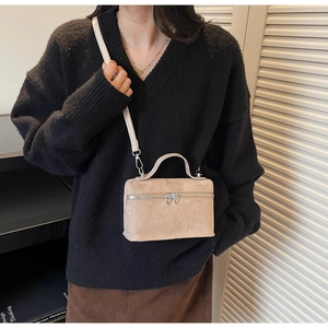 Detail of a beige crossbody bag featuring a unique heart-shaped zipper and matte finish