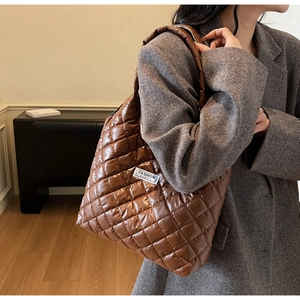Close-up of brown quilted glossy fabric and white logo label on the padded tote bag