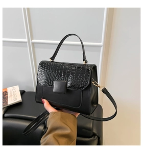 Détail d'un sac à main noir en similicuir avec motif crocodile et détails dorés