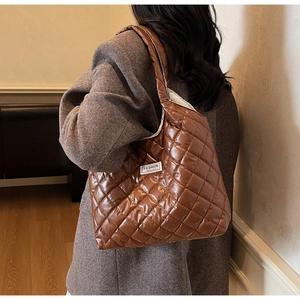 Close-up of quilted diamond pattern on brown crossbody bag with fashion label detail