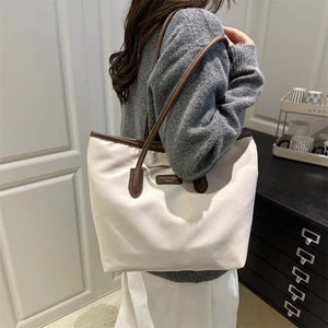 Minimalist white tote bag with deep brown leather straps in a stylish commuter look