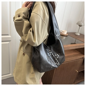 Gros plan du sac fourre-tout en cuir noir mat avec des rivets argentés en forme d'étoile