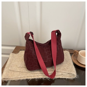Detail of burgundy leopard print shoulder bag with wide strap on beige knit mat