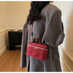 Detail of red suede crossbody bag featuring unique silver heart-shaped metal zippers