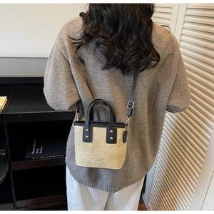 Detail of a two-tone bucket bag with adjustable shoulder strap shown on a model
