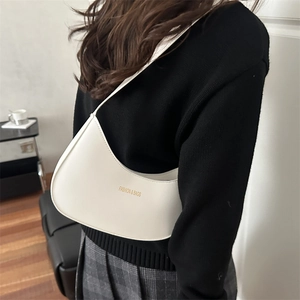 Minimalist white leather hobo bag with gold lettering shown on a model's shoulder
