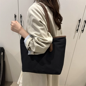 Minimalist large black nylon tote bag with brown leather straps for autumn winter 2025