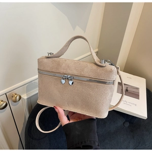 Detailed macro view of beige faux suede handbag with decorative silver heart zippers