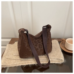 Detail of coffee leopard print shoulder bag with plush texture and wide woven strap