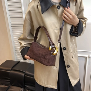 Petit sac rétro marron en daim avec chaîne dorée porté par un mannequin élégant