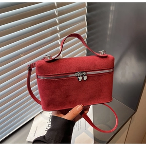 Detail of red suede crossbody bag with heart-shaped silver zippers and sleek handles