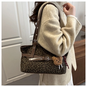 Close-up of leopard print tote bag with plush charm and detailed leather strap stitching