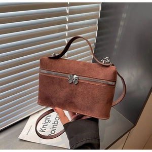 Detail of brown suede crossbody bag featuring unique heart-shaped silver zipper pulls
