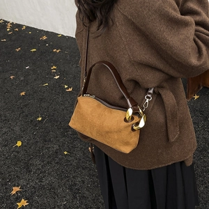 Sac oreiller en daim marron avec chaîne dorée dans un cadre extérieur automnal élégant