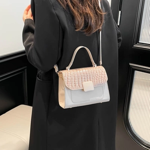 Chic cream crossbody bag with faux crocodile flap shown on a model wearing a black coat