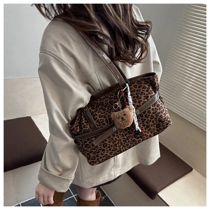 Detail of leopard print tote bag with brown faux leather straps and plush bear charm