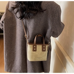 Detail shot of khaki bucket bag with embossed leather texture on a checked suit model