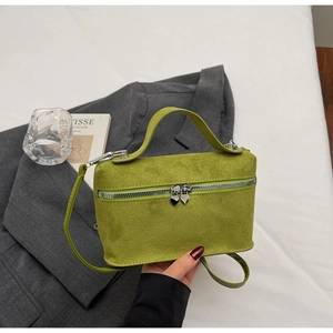 Detail of lime green suede handbag featuring heart-shaped zippers and a top handle