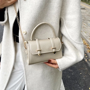 Petit sac bandoulière métallisé champagne avec chaîne dorée porté par un mannequin