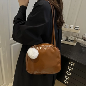 Brown glossy PU leather shoulder bag for women with a white plush pom-pom charm