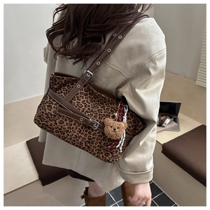 Detail of leopard print tote bag with plush bear charm and brown leather shoulder strap