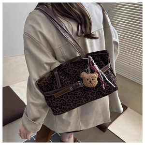 Detail view of leopard print tote bag with brown leather trim and cute bear charm