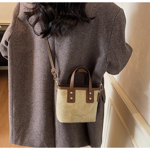 Detail of beige suede bucket bag with leather handles and fashion logo print