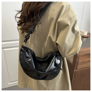 Détail du sac hobo en cuir verni noir avec bandoulière nouée et breloque perle