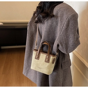 Detail of contrast-color suede tote bag with leather straps and golden rivet accents