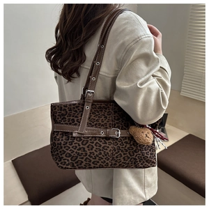 Detail of leopard print tote bag with brown leather strap and plush bear charm decoration