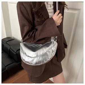 Gros plan d'un sac demi-lune argenté métallisé porté sur un blazer marron élégant