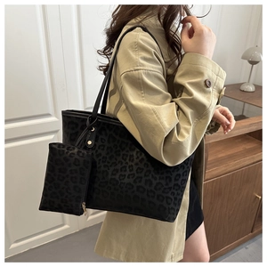 Close-up of black leopard print tote bag with matching pouch on a trench coat model