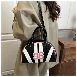 Gros plan d'un sac bowling rétro noir avec bordures roses porté avec un trench-coat kaki