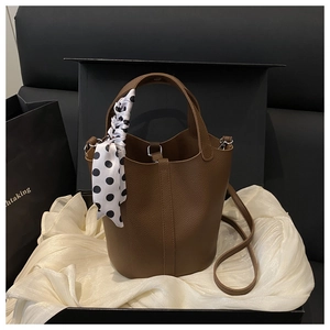Close-up of caramel lychee grain leather bucket bag with polka dot silk scarf in gift box