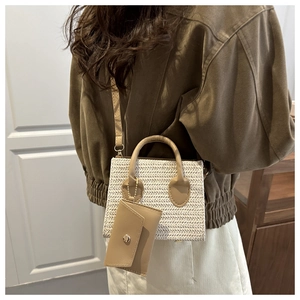 Close-up of a white woven mini crossbody bag with leather trim worn by a model