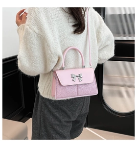 Detail shot of a pink bow square bag with sequins and silver bow on a beige sweater