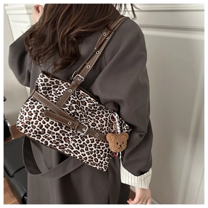 Detail of leopard print tote bag with leather strap and plush bear charm on model