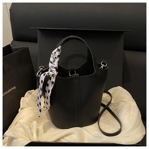 Detail of black lychee grain bucket bag with polka dot silk scarf on gift box